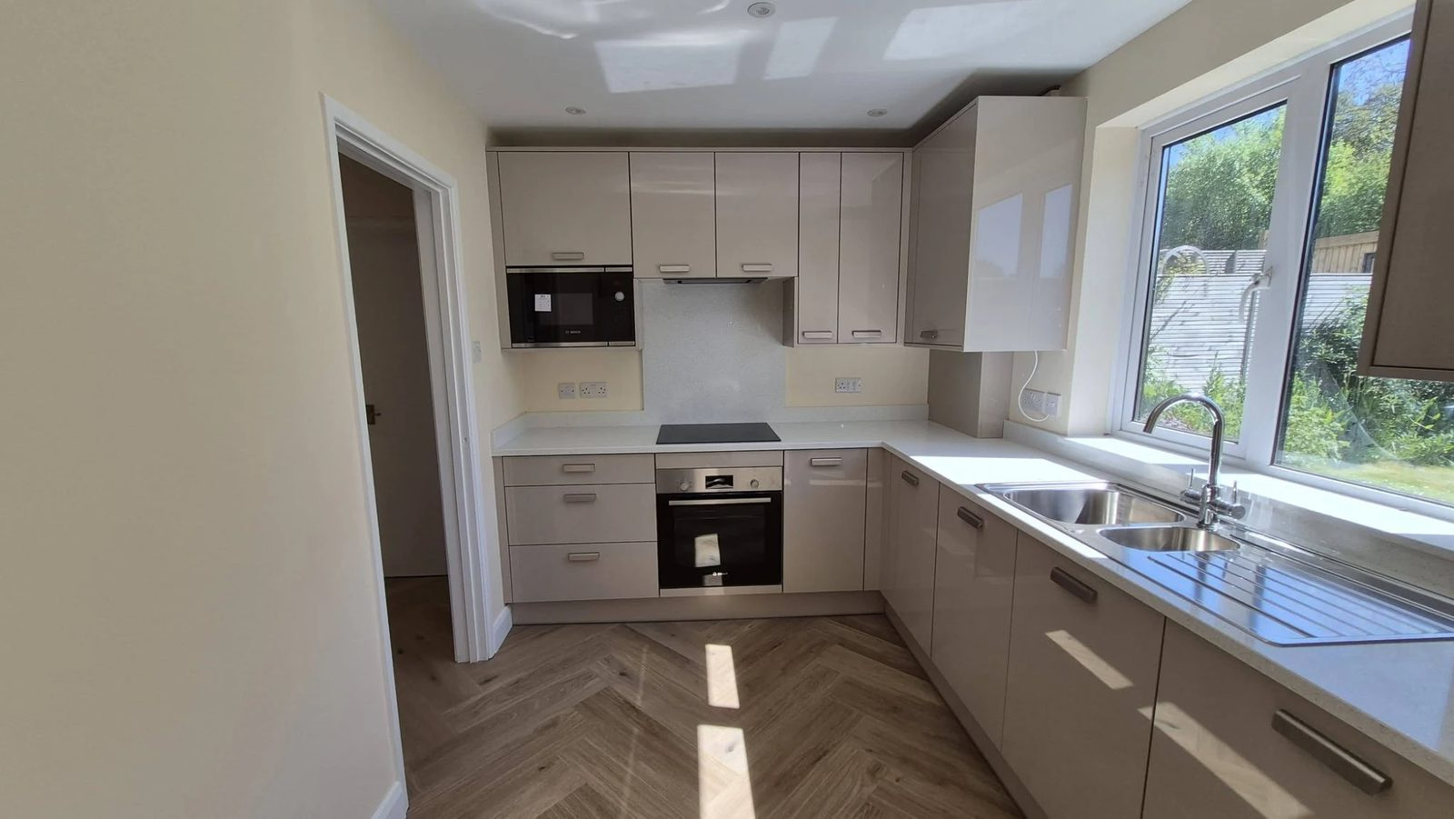 Fitted kitchen with gloss units and herringbone flooring