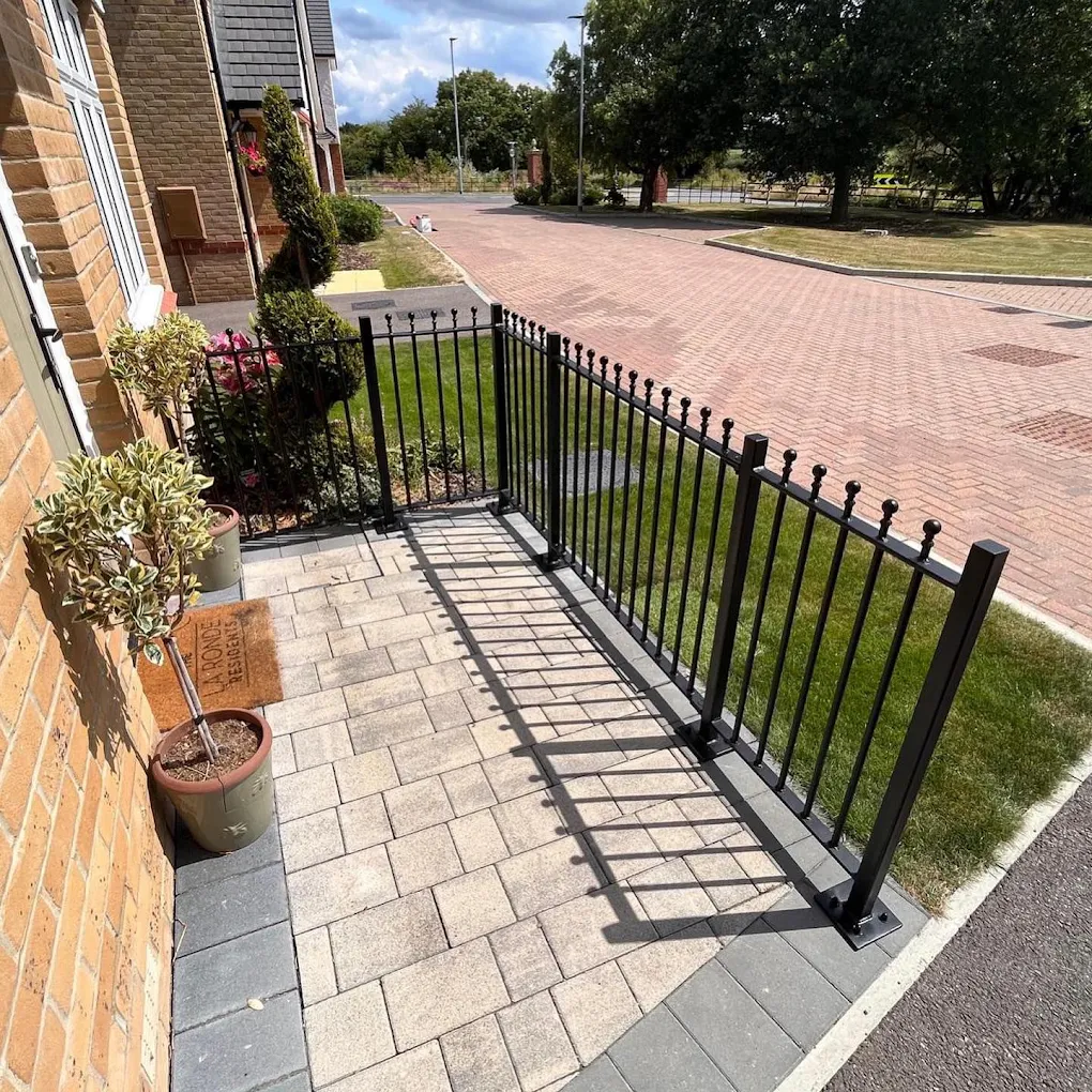 Black railings and block paved front garden on a brick terrace