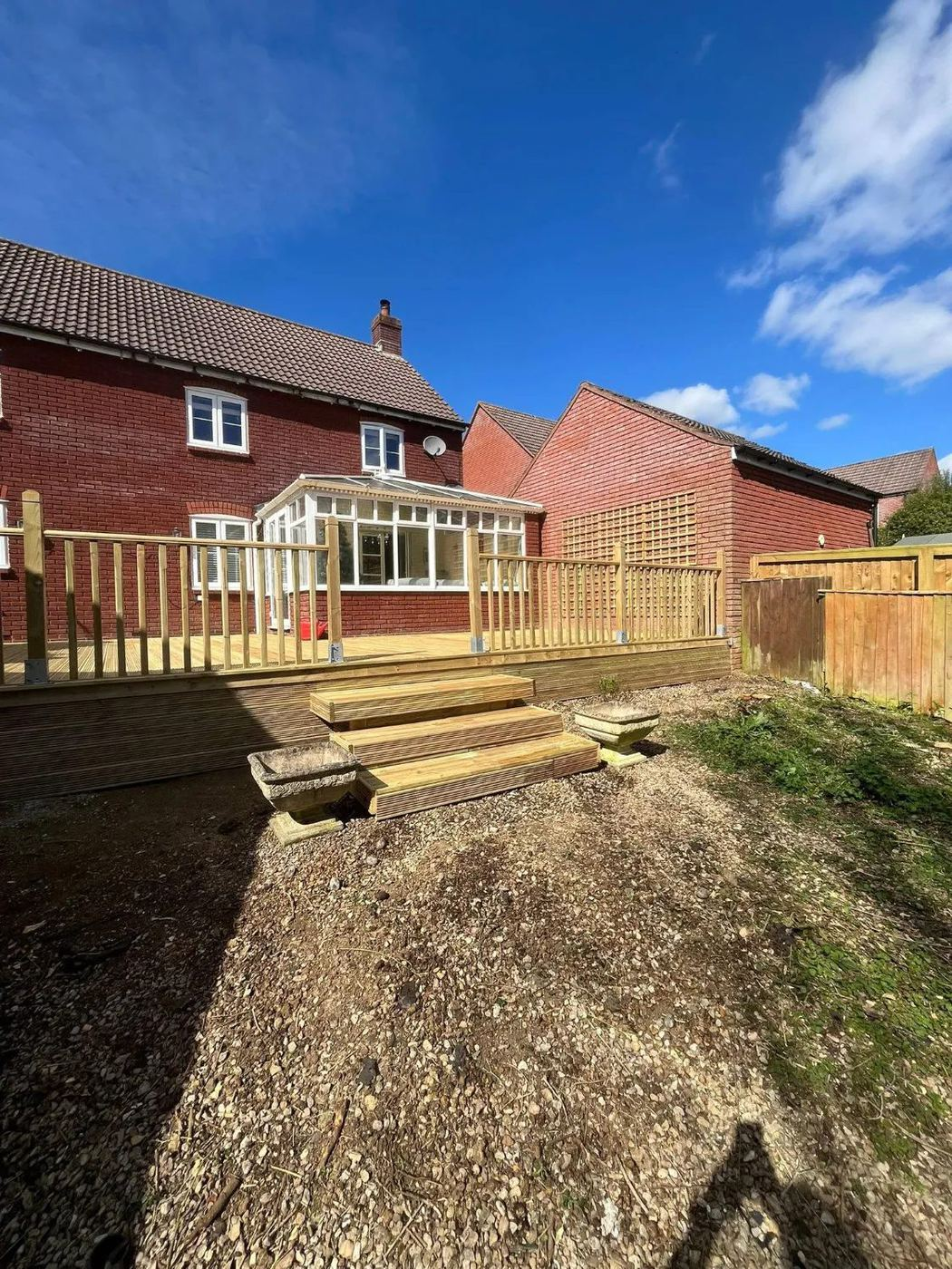 Raised decking with balustrade and steps beside a conservatory